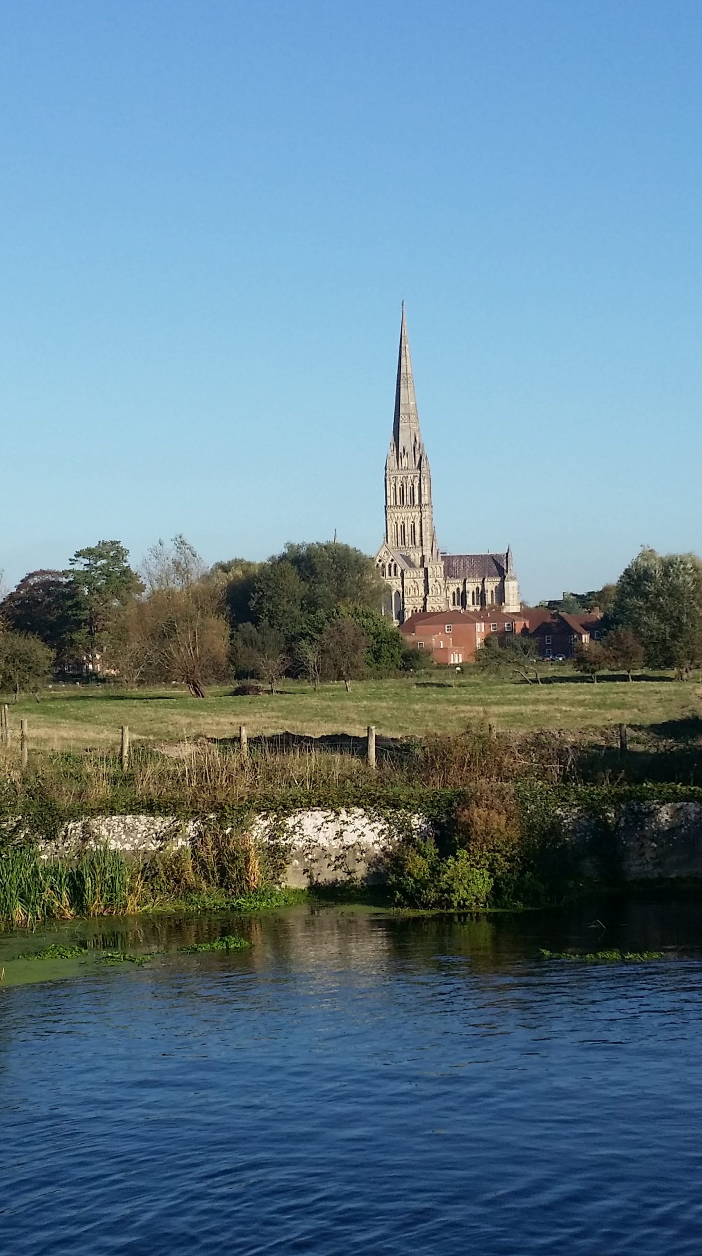 in the background a cathedral with a big spire, with farmland and a river in the foreground