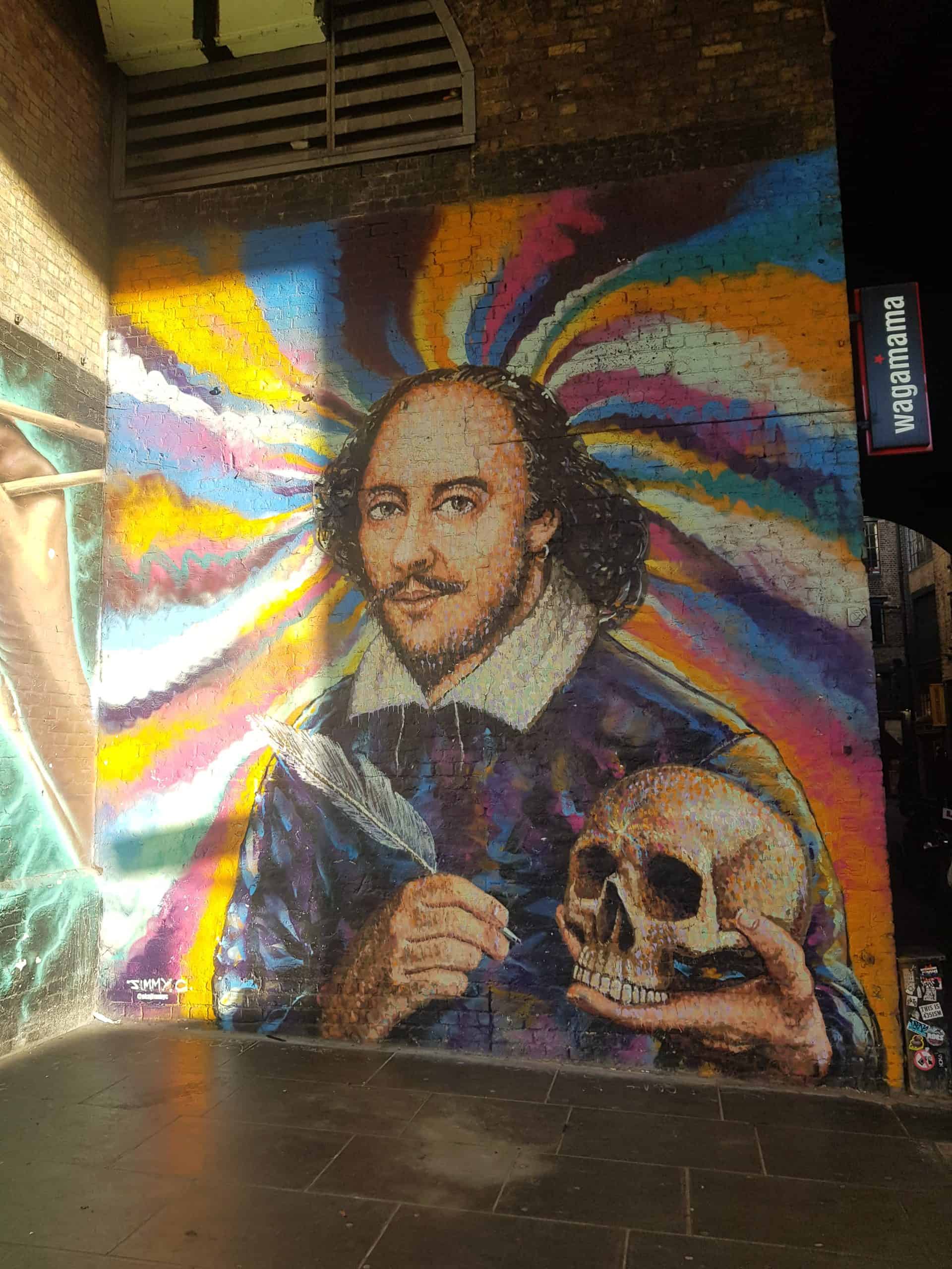A street art portrait of shakespeare holding a quill and a skull