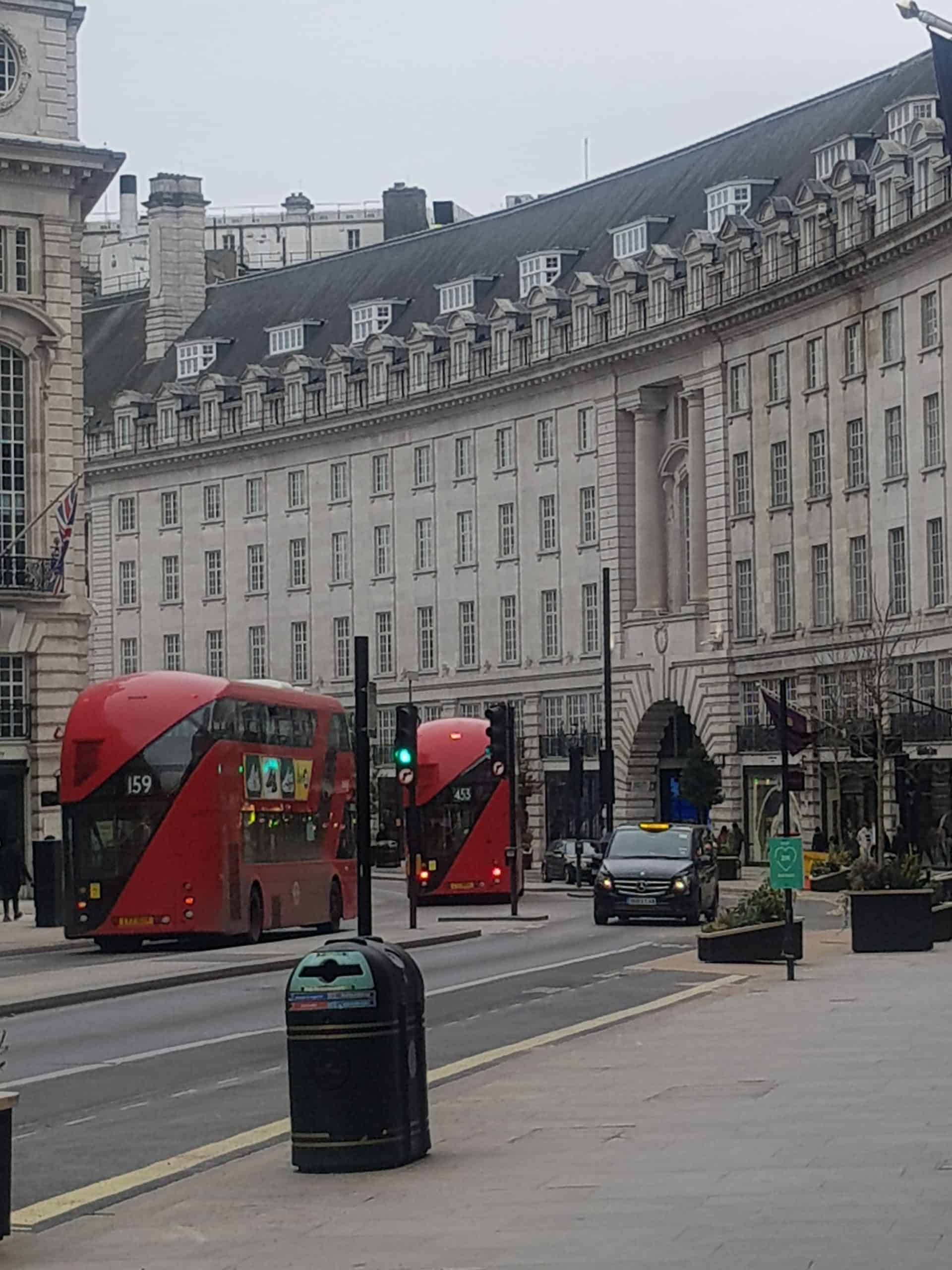 photo of Regents street with the white stone Georgian style buildings  and 2 red double decker buses going up the street. 