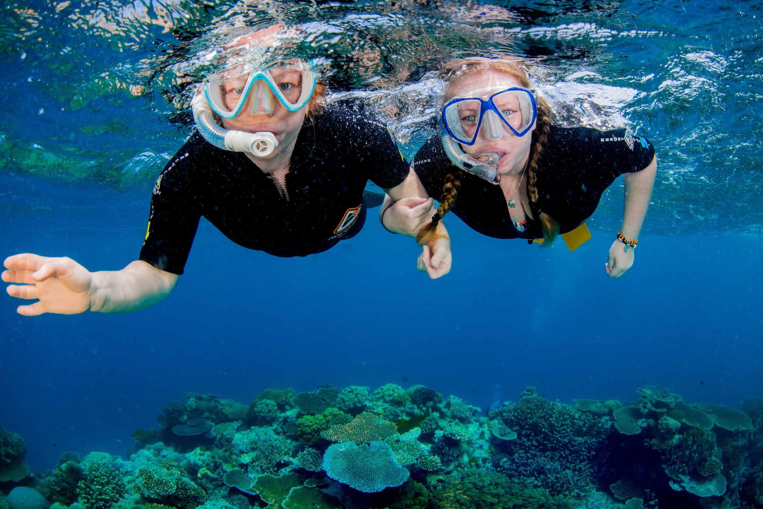 the blogger with her sister Snorkeling underwater with some coral underneath them.
