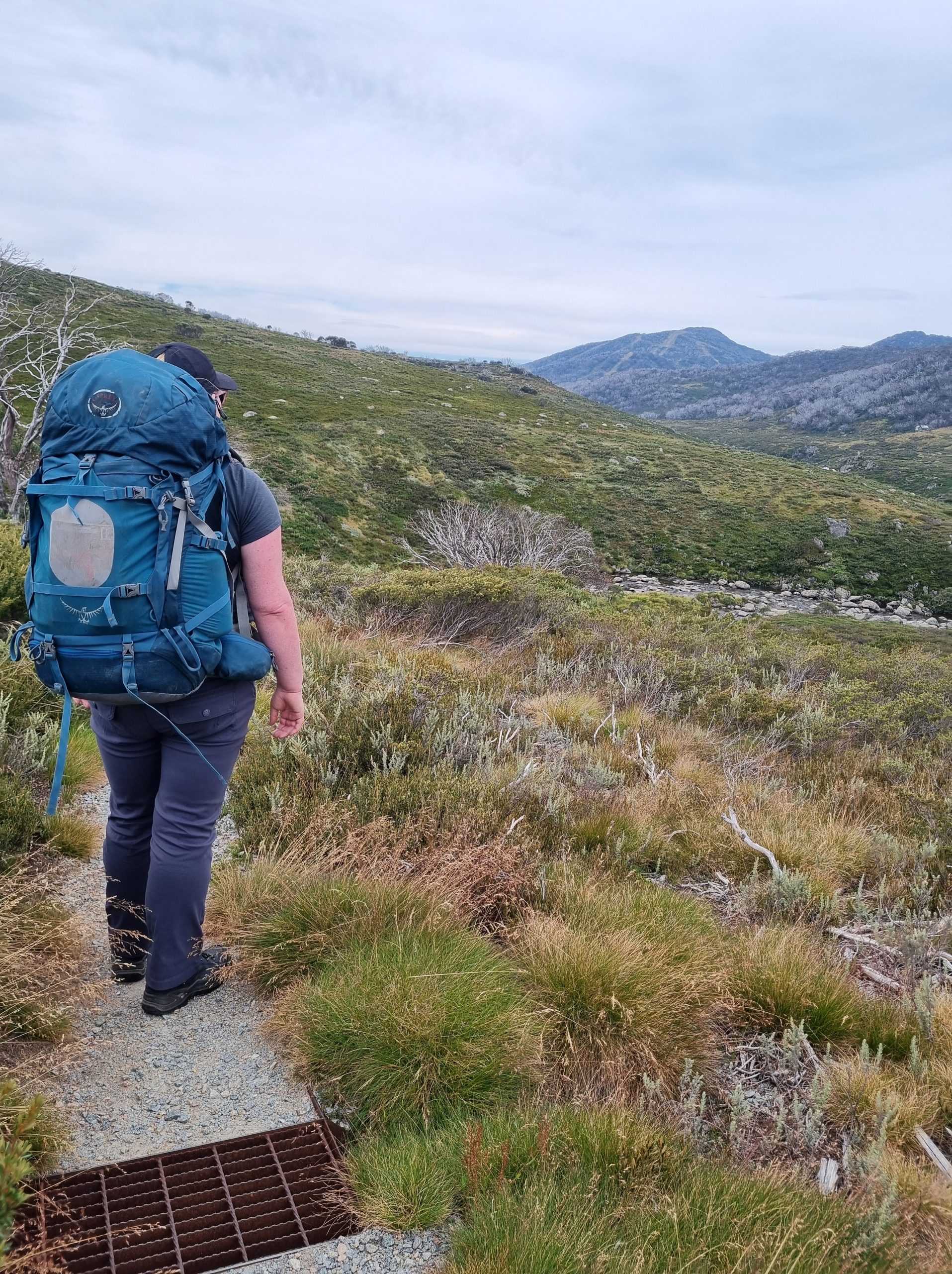 a photo of the blogger with her pack on, facing away from the camera looking at the view of the rolling mountains in the distance