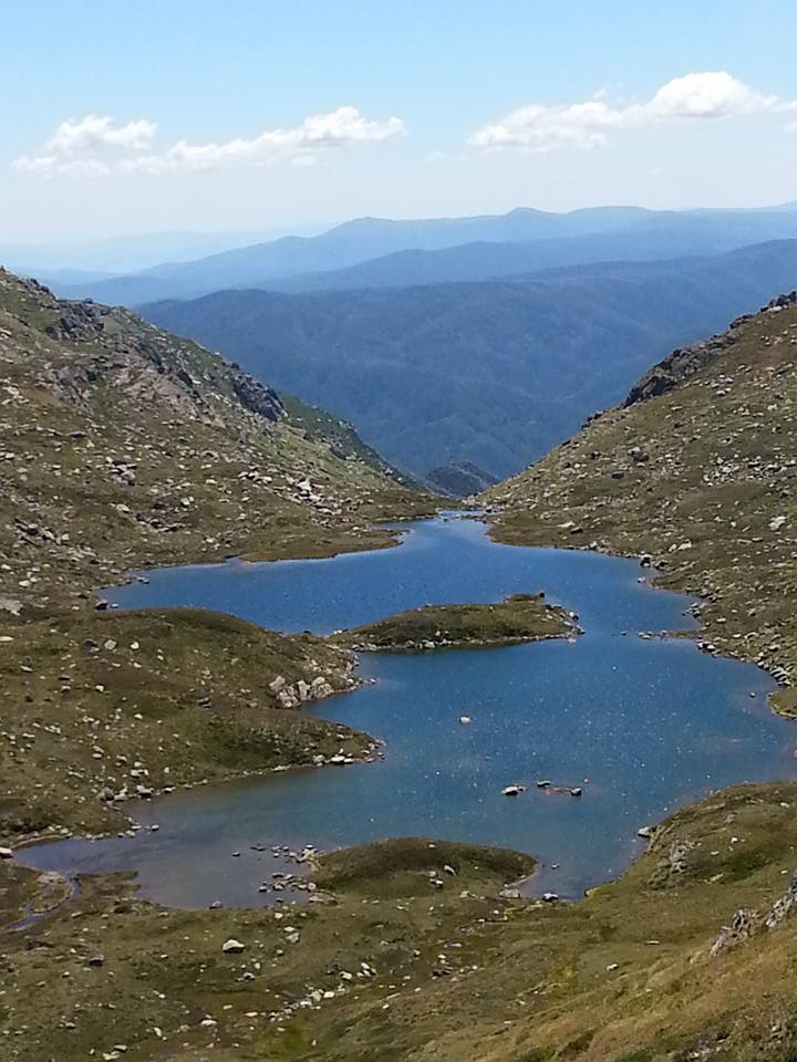 a view from the top of the glacial blue lake with the mountains in the background