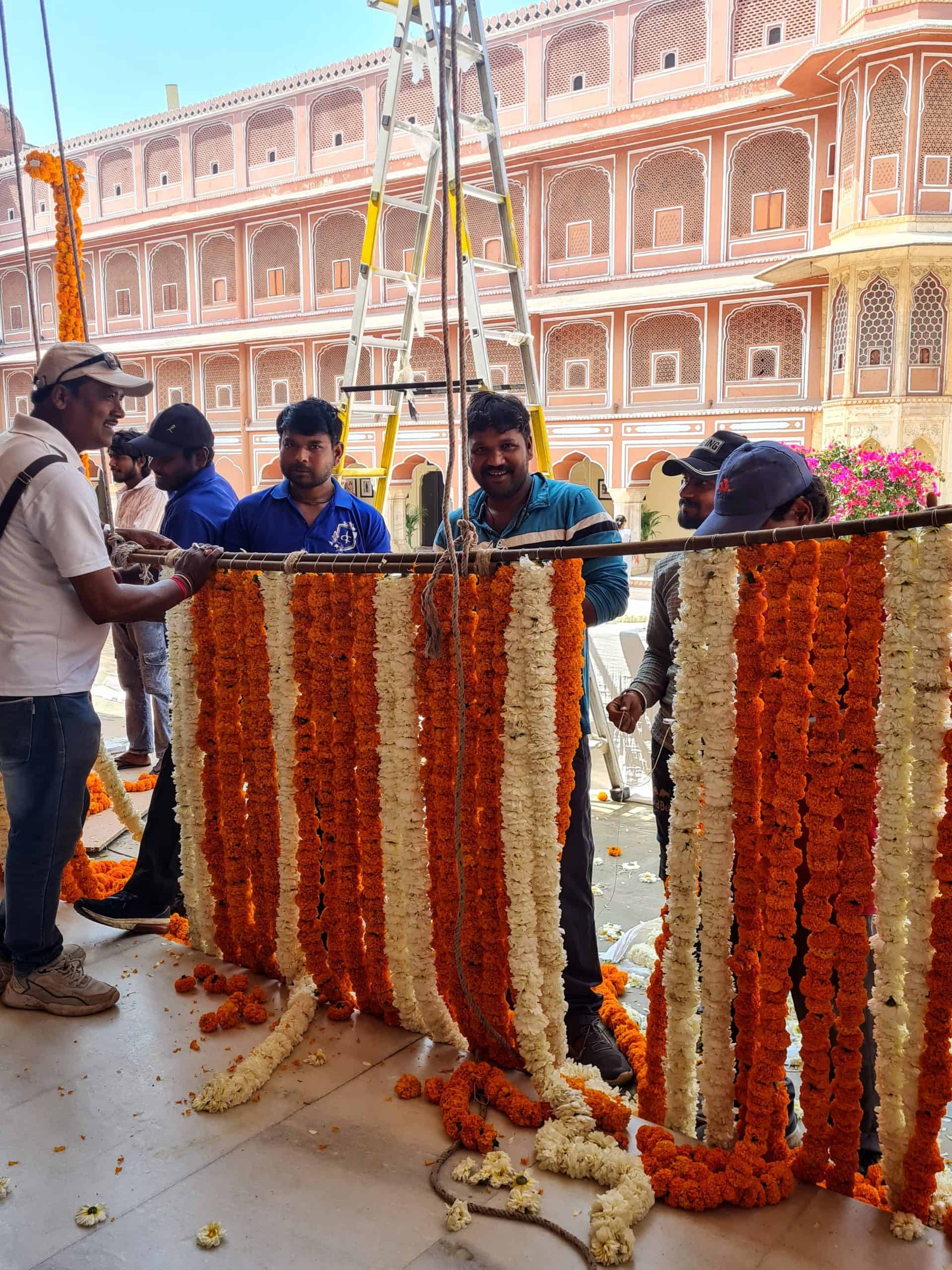 a group of men making chains of marigold flowers as decorations for holi