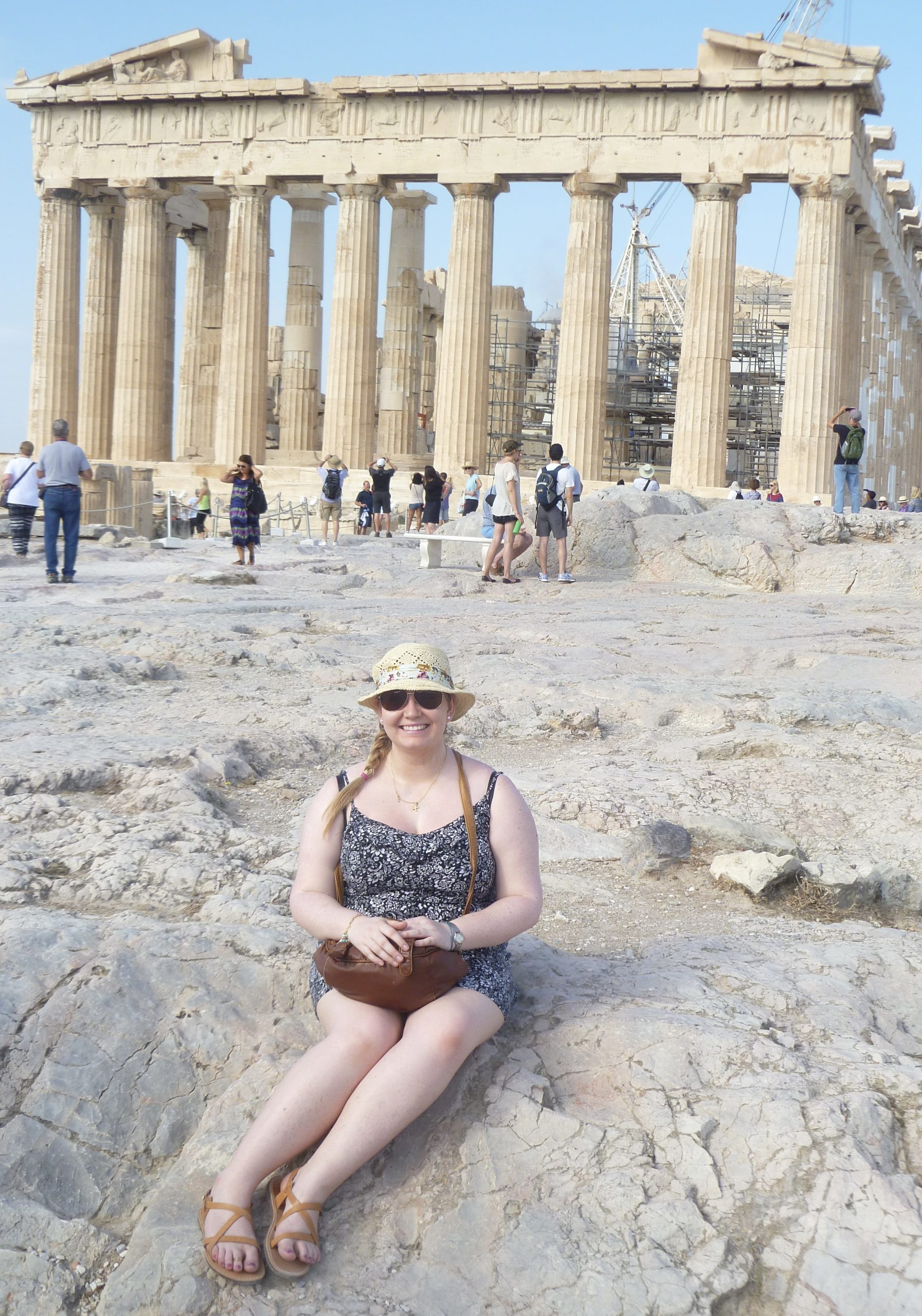 the blogger sitting in front of the pillars of the Parthenon at the acropolis in Athens